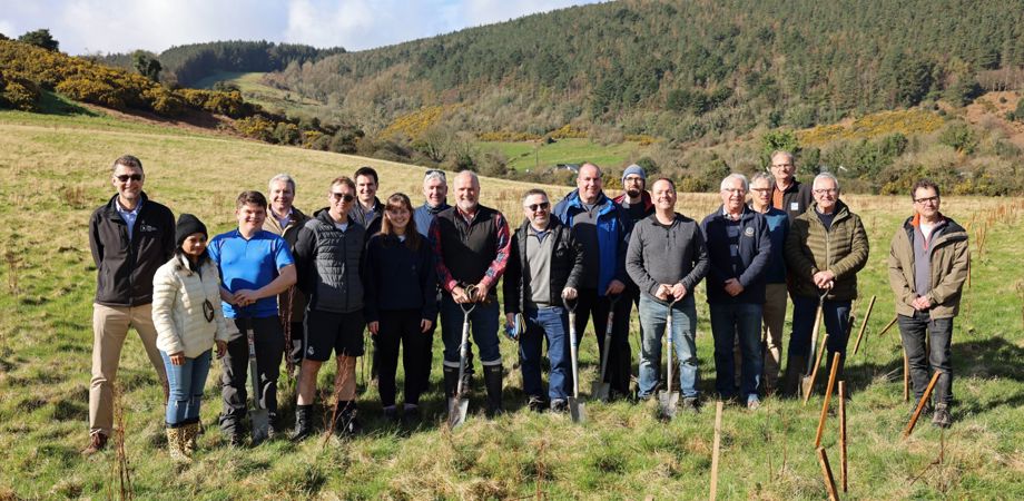 A large group of people posing with shovels with the Manx hillside in the background