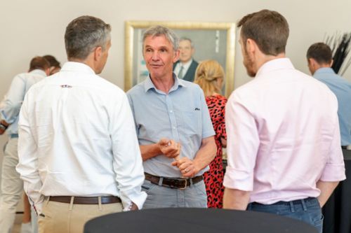 Three men speaking at a formal social event
