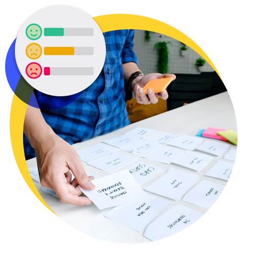 An image of a person laying out UX design cards on a table with sentiment icons overlaid