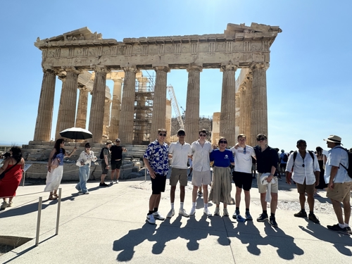 A photo of Hannah and the ArthEsy team posing for a photo in front of the Parthernon in Athens