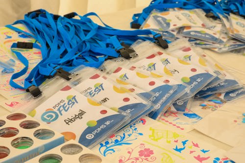 A pile of PDMS Fest lanyards displayed on the table with the top lanyard reading 'PDMS Fest - Abigail'
