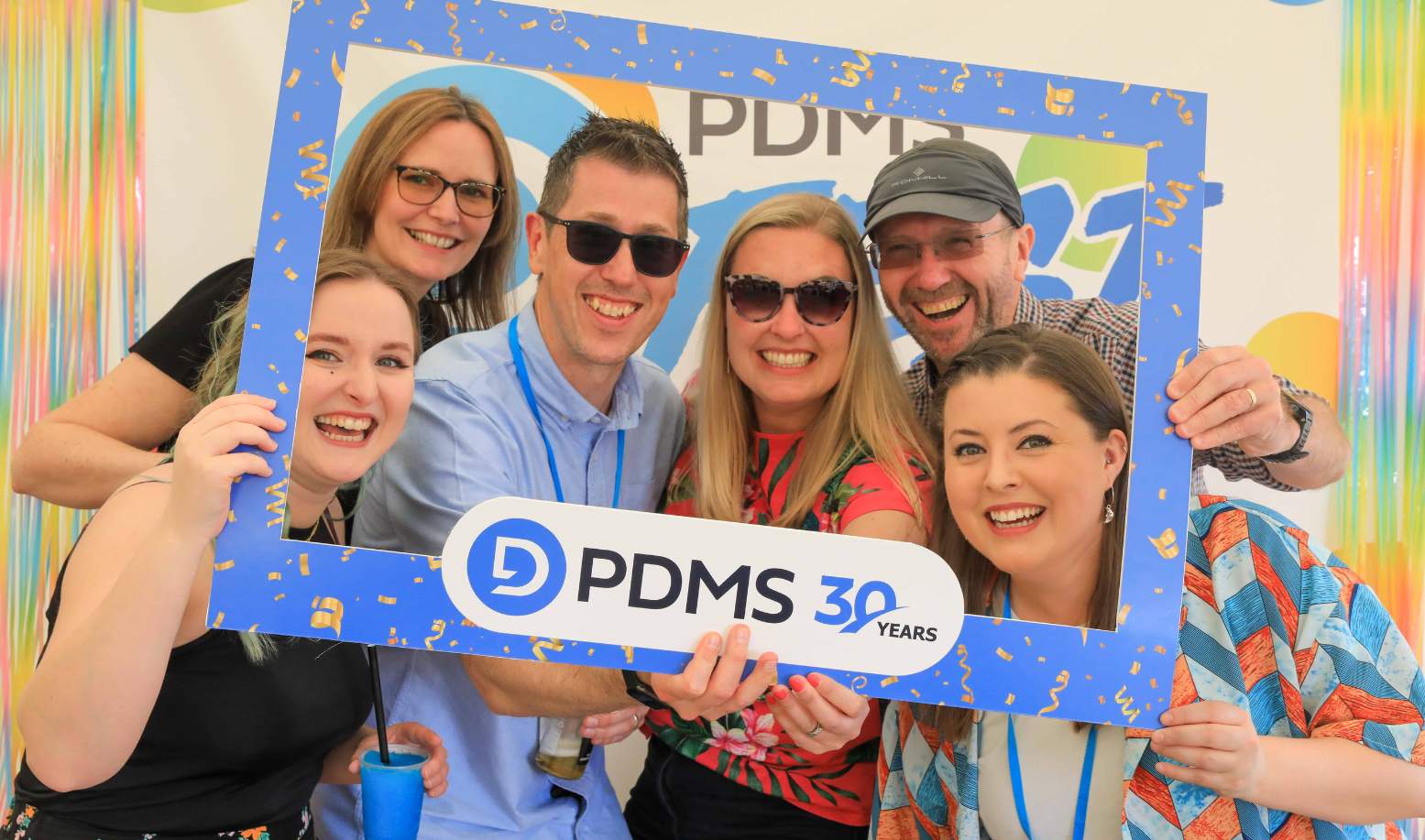  A group of people smiling for a photo with a PDMS 30 years frame