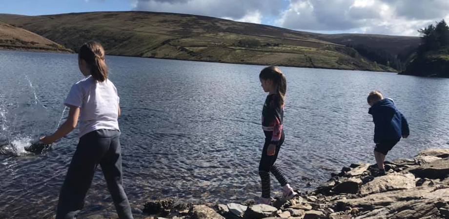 A picture of author of the article, Kathryn's children throwing stones into a reservoir 
