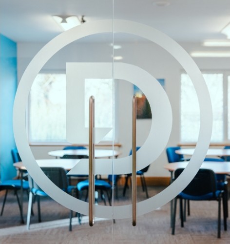 A photo of the PDMS icon on a glass door into a breakout area in the PDMS office