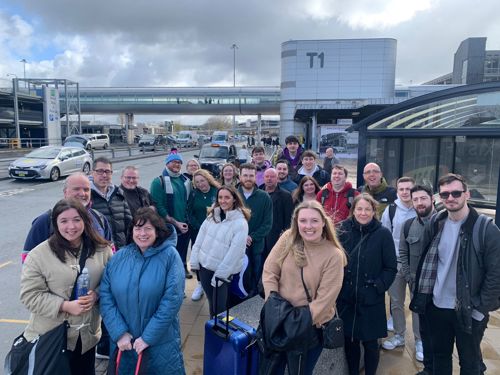 A large group of people posing for a photo at Manchester Airport