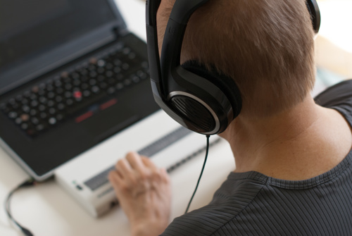 Blind person using a screen reader and headphones to use a laptop