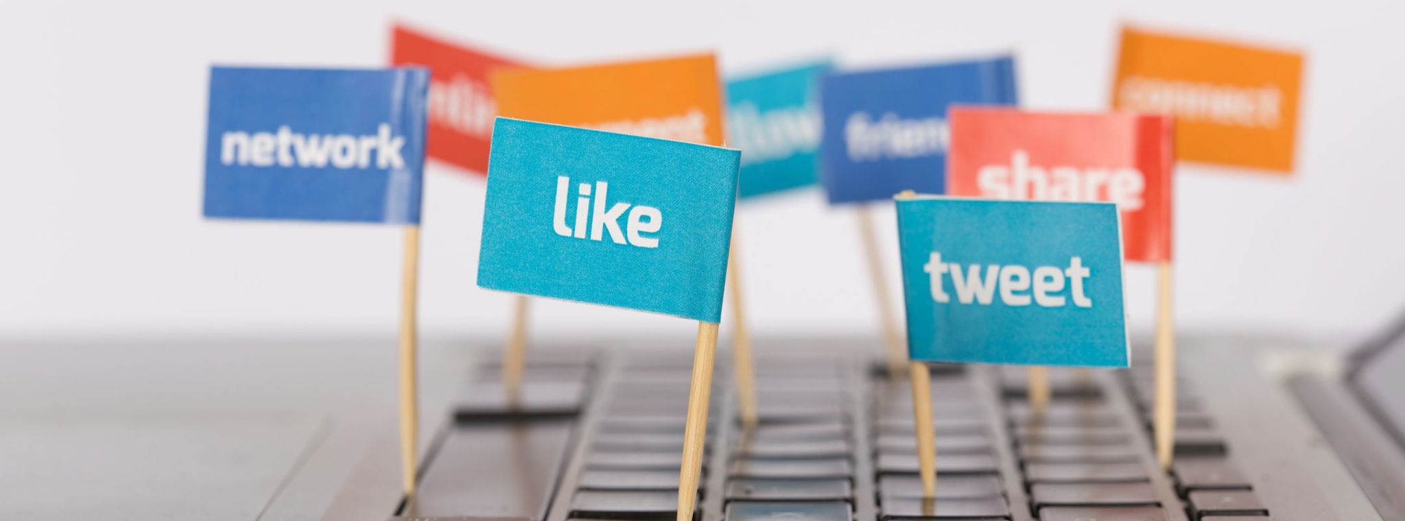 A photo of a laptop keyboard with small flags sticking out and displaying social media terms