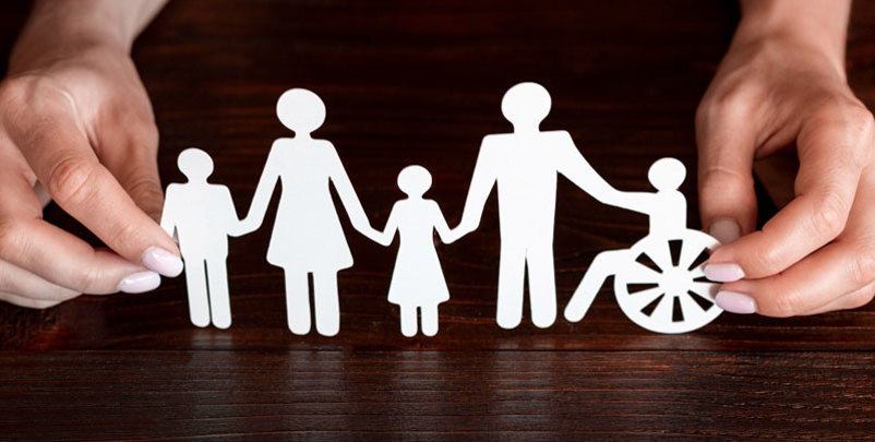 A person holding a paper cutout displaying a range of people to demonstrate accessibility and inclusive technology