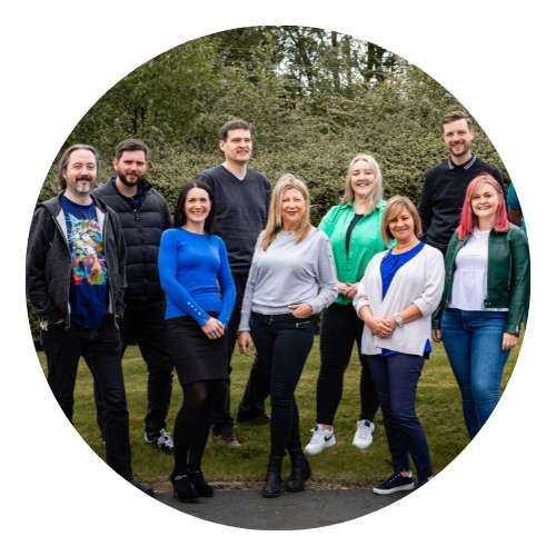 A group of people smiling and standing on grass bank