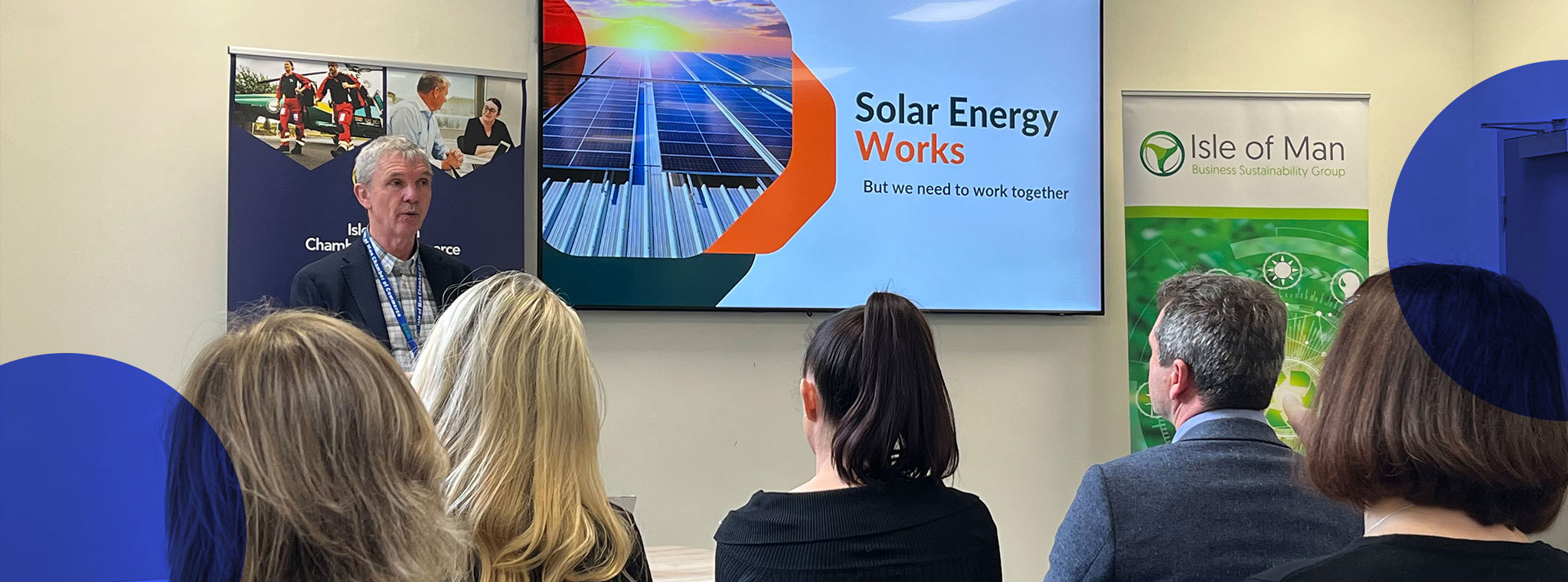 Chris Gledhill presenting in front of a screen reading 'Solar Energy Works' to a room of attendees