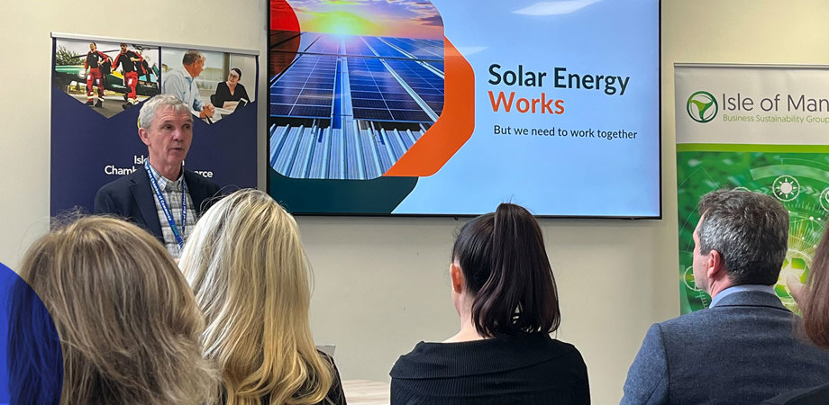 Chris Gledhill presenting in front of a screen reading 'Solar Energy Works' to a room of attendees