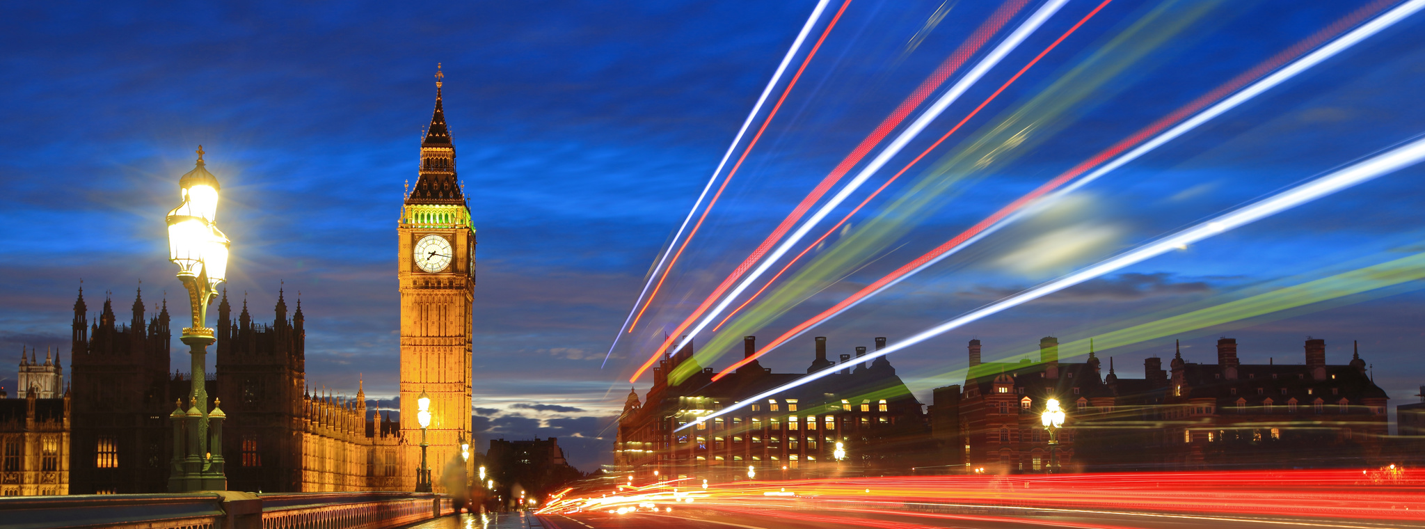Timelapse photo of Big Ben with lights from traffic blurred in the foreground to indicate movement