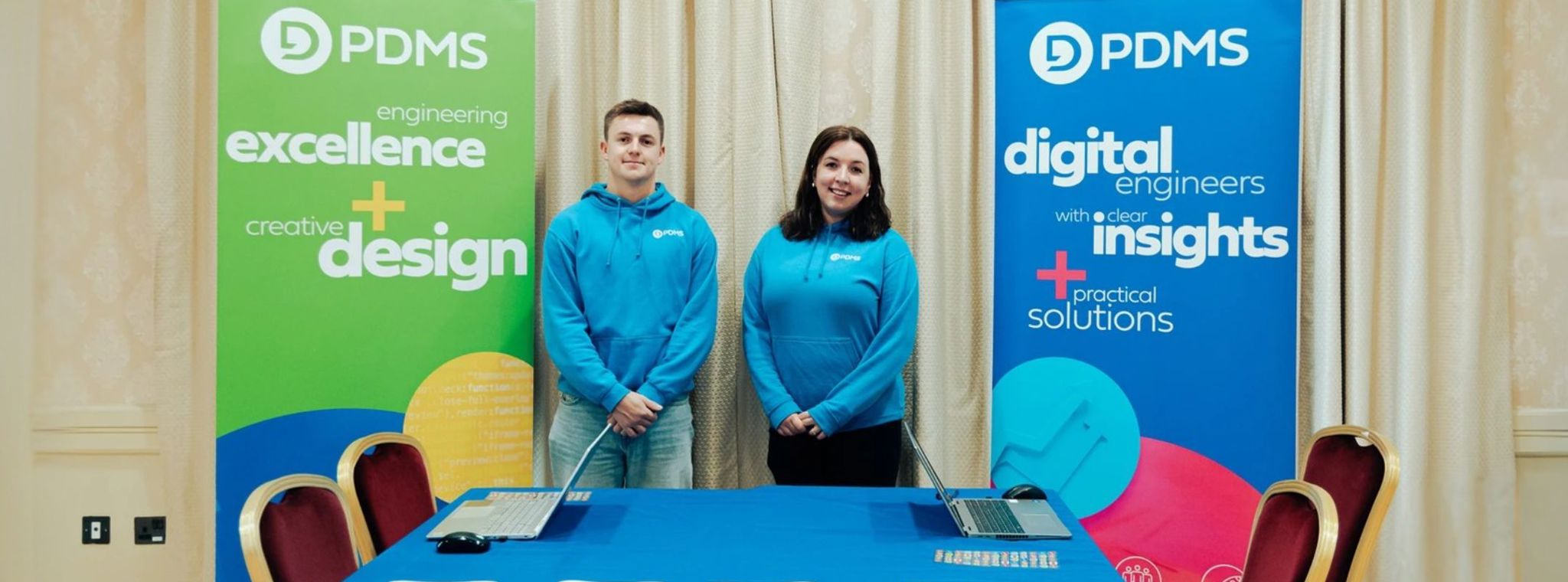 A photo of Rob and Hannah stood behind the PDMS stand at STEMFest