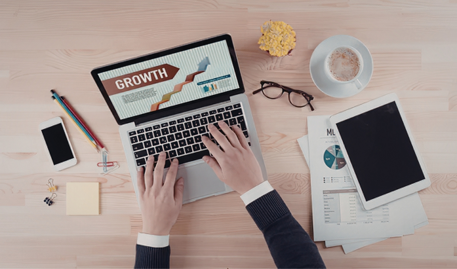  A photo of a desk with a laptop and marketing materials with two hands using the laptop