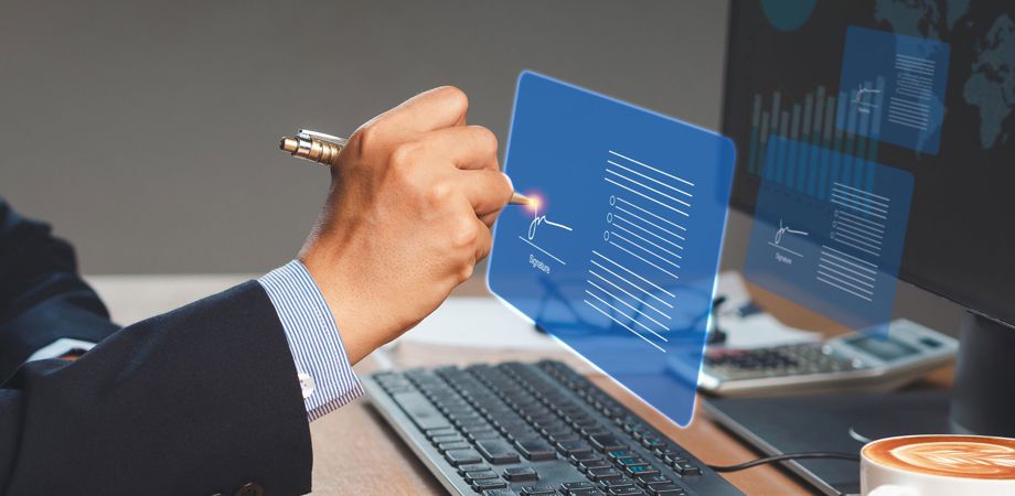 An image of a businessman signing a digital contract in front of a computer