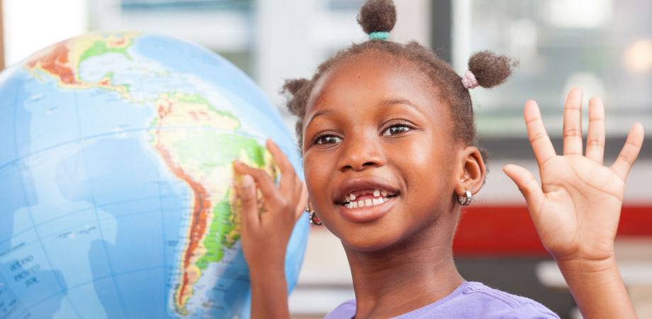 An image of a little girl pointing at South America on a globe