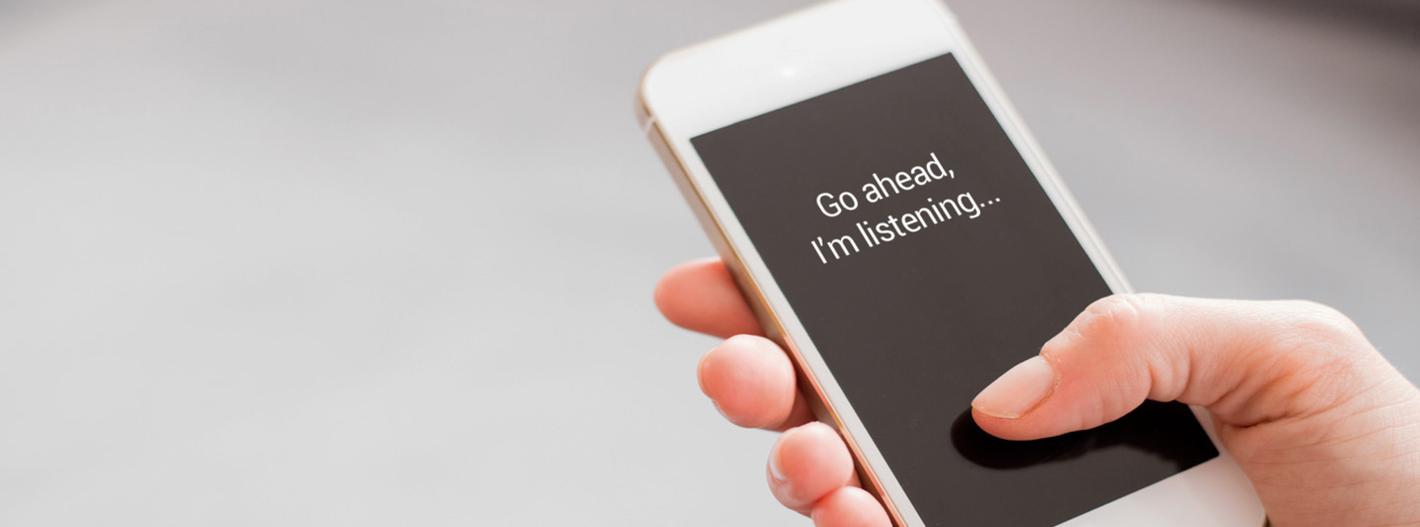 A phone in somebodies hand displaying the message "Go ahead, I'm listening..."