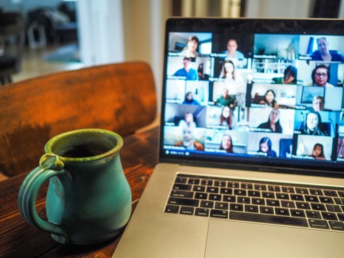 Photo of a laptop screen displaying lots of people on a video call enjoying a webinar