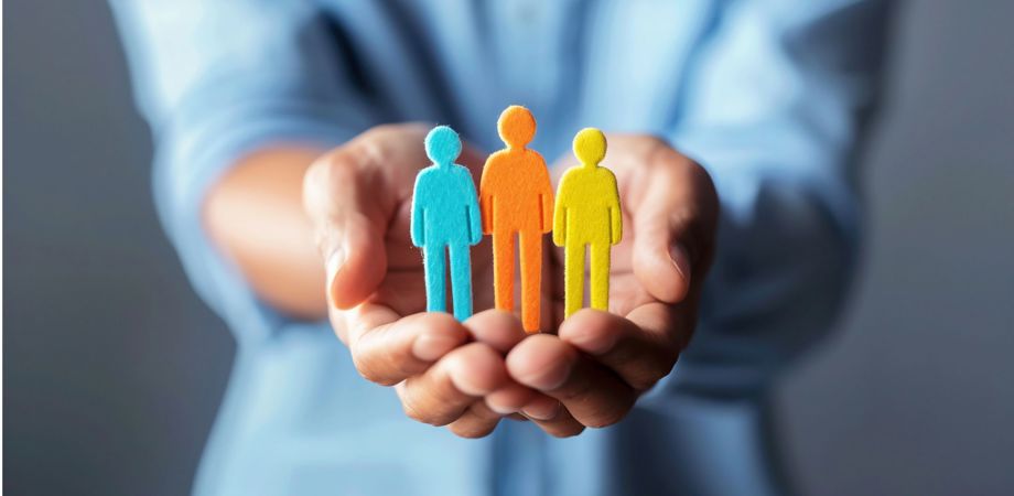 An image of a person holding a three felt people in blue, orange and yellow to represent employee wellbeing