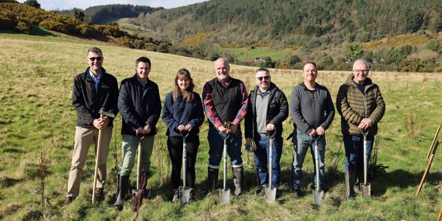 Seven people lined up with shovels for a photo