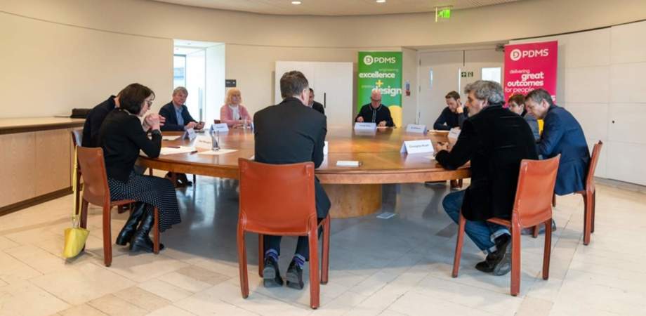 A photo of roundtable participants sat around a table having a discussion