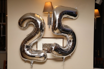 Balloons in the shape of 25 in front of a light and picture on a wall