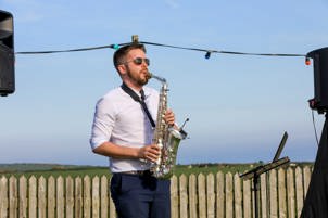 Musician Chris Sullivan playing the saxophone outdoors