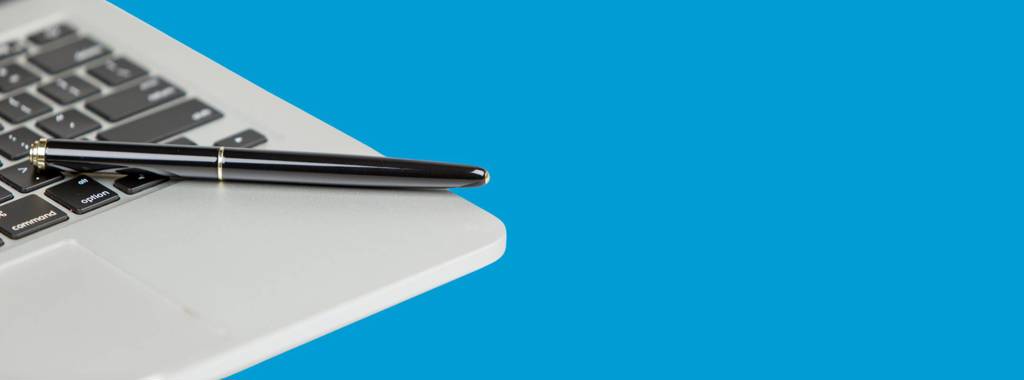 An image of a laptop with a pen balancing on the keyboard