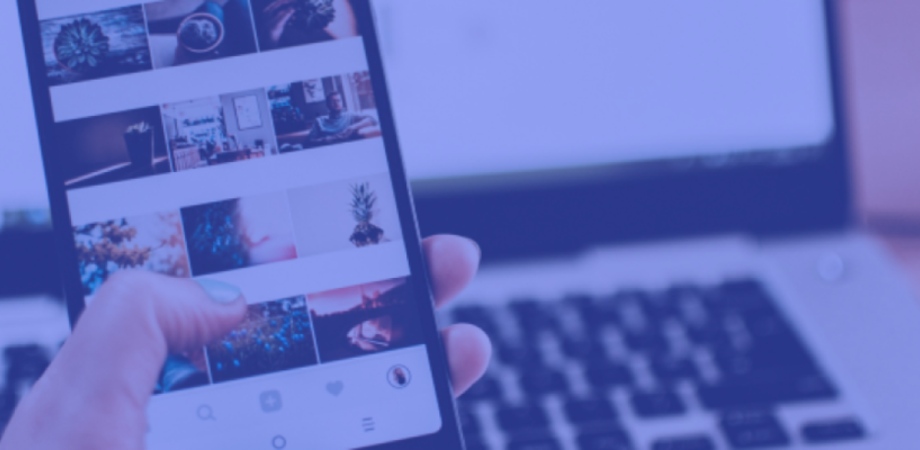 An image of a female holding a mobile phone with images on it infront of a laptop